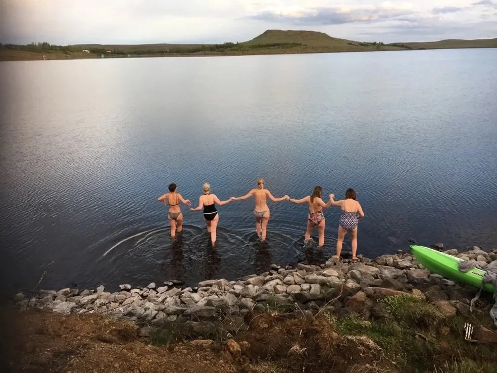 A small group walking into a lake at dusk